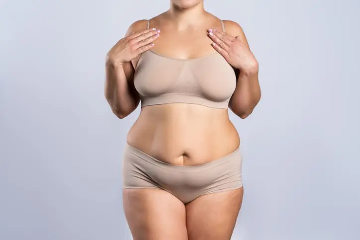  Woman in beige underwear on gray background, overweight female body